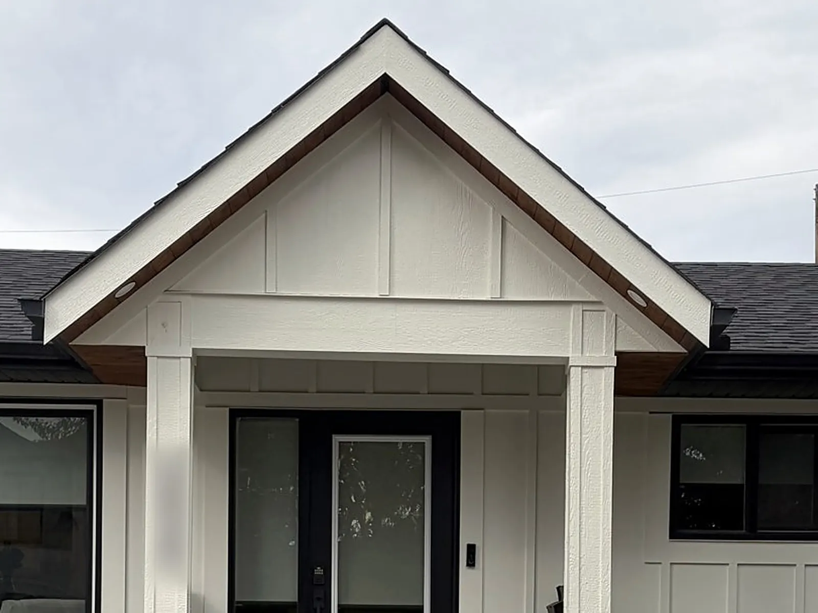 The same bungalow after: clean white board-and-batten, black door and trim