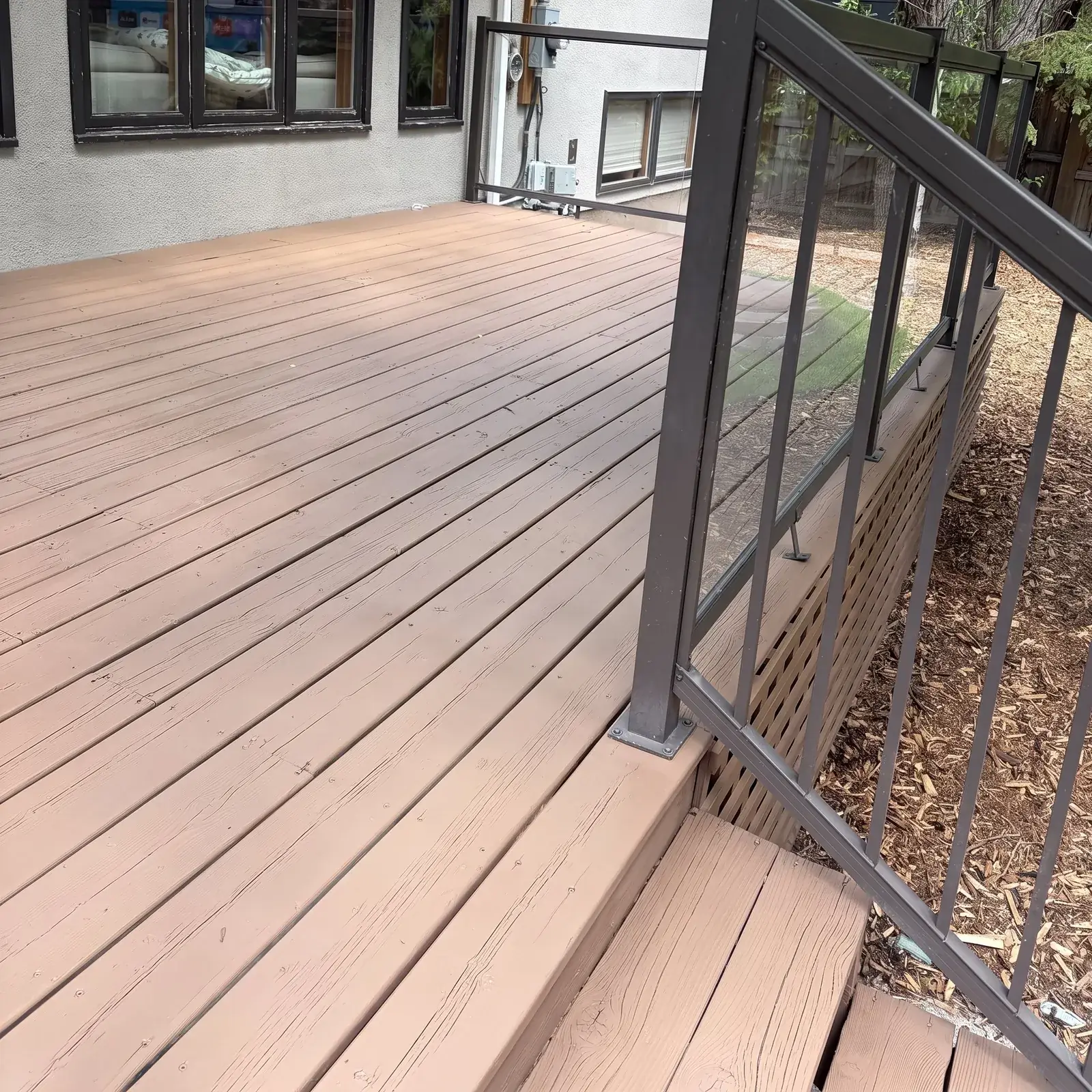 A long taupe deck with a dark metal and glass railing