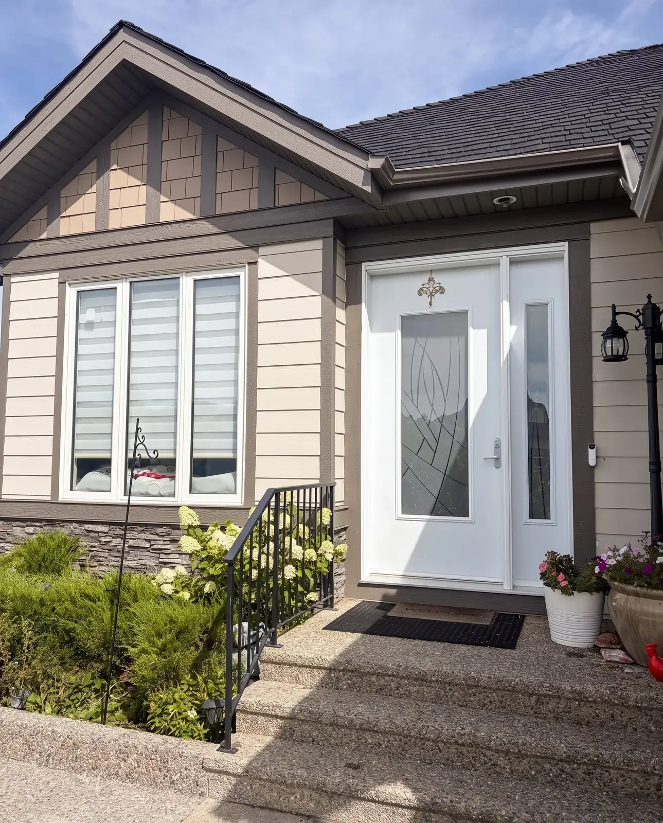 A bungalow front entry with a white door, taupe siding and dark trim